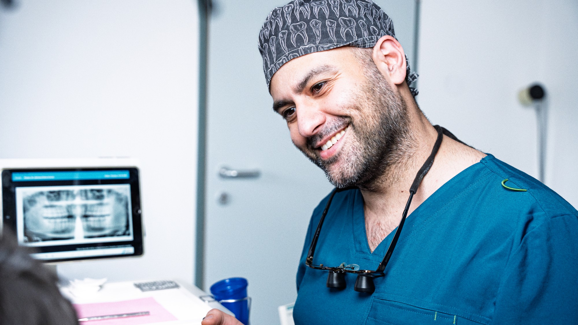 Dr. Dr. Onur Dogru im Gespräch mit einem Patienten, Röntgenbild am Tablet